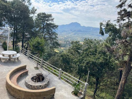 a bench and a table on a hill with a view at Hotel El Mirador y Jardin in Tlayacapan