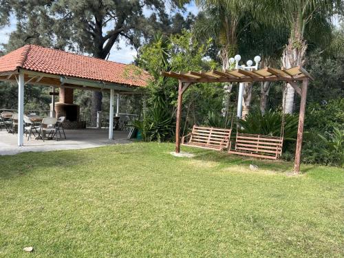 a wooden pergola with a table and chairs in a yard at Hotel El Mirador y Jardin in Tlayacapan