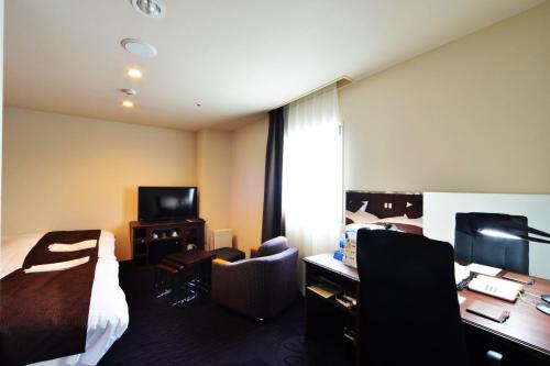 a hotel room with a bed and a desk and a tv at Kushiro Century Castle Hotel in Kushiro