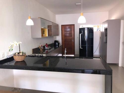 a kitchen with a black counter top and a refrigerator at Casa pé na areia em Gamboa do Morro de São Paulo in Cayru