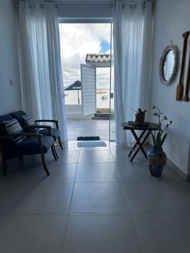 a living room with a large window and a couch at Casa pé na areia em Gamboa do Morro de São Paulo in Cayru