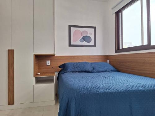 a bedroom with a bed and a desk and a window at Apartamento novo, perto da praia e conveniências in Salvador