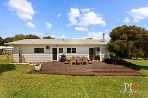 a white house with a deck with tables and chairs at Smith Beach Family House Sleep 6 in Smiths Beach