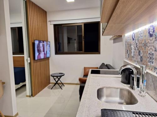 a kitchen with a sink and a living room at Apartamento novo, perto da praia e conveniências in Salvador