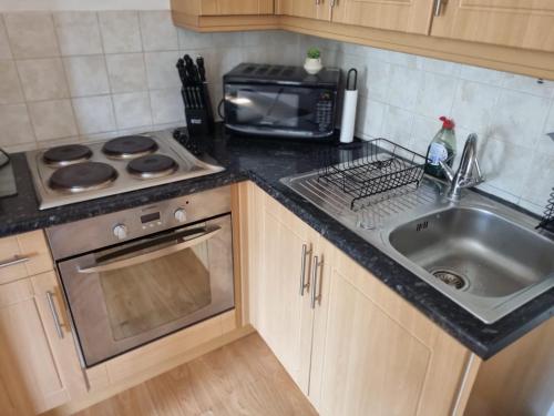 a kitchen with a sink and a microwave at UK Chaps Retreat: Balcony Apartment in London