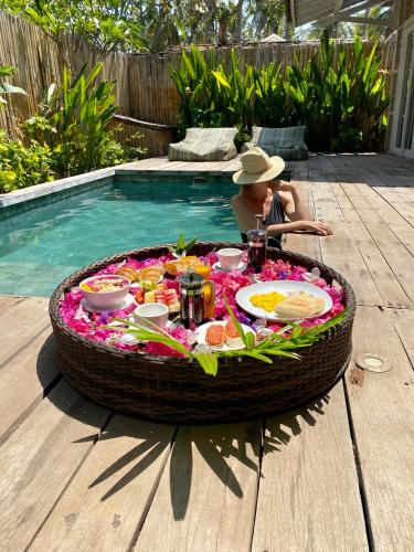 a child sitting at a table with a large tray of food at Villas Edenia - Luxe Villas with Private Pools in Gili Trawangan