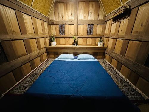 a room with a blue bed in a wooden room at Toraja Homestay & Coffee Bunna in Rantepao