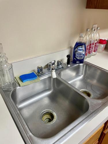 a stainless steel sink in a kitchen with cleaning products at Bayou and Beyond: The perfect stay in Monroe