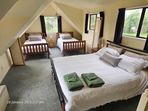 1 dormitorio con 2 camas y toallas verdes. en Country Cottage Rotorua, en Whakatahuri