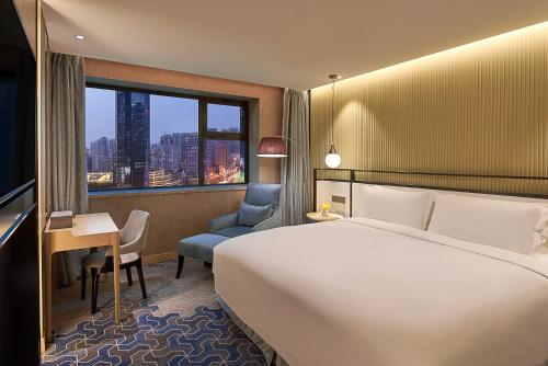 a hotel room with a bed and a desk and a window at The Westin Shenyang in Shenyang