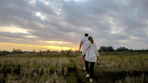 a man and a woman walking through a field at Kusfarm Bali by AHM in Selemadeg
