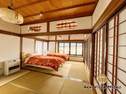 a bedroom with two beds and a large window at Arai Villa Myoko in Myoko
