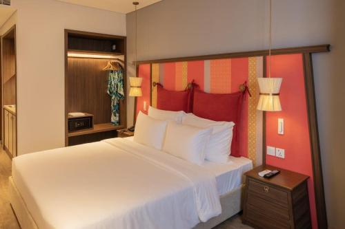 a bedroom with a large white bed with a red headboard at M Continental by Mandala Mui Ne in Phan Thiet