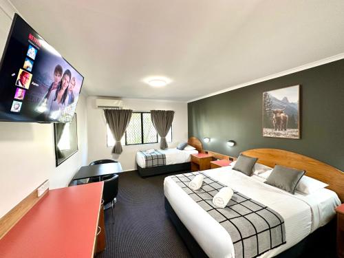 a hotel room with two beds and a flat screen tv at Mackay Resort Motel in Mackay