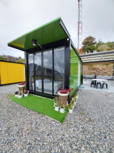 a green house with plants on a gravel yard at SF Homestay in Kundasang