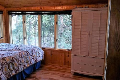 ein Schlafzimmer mit einem Bett und einem großen Fenster in der Unterkunft Treetop Cottage-Dog Friendly No Fees, Mill Lake, Hot Tub, Kayak, Paddle Boat, Row Boat, Firepit in Gobles