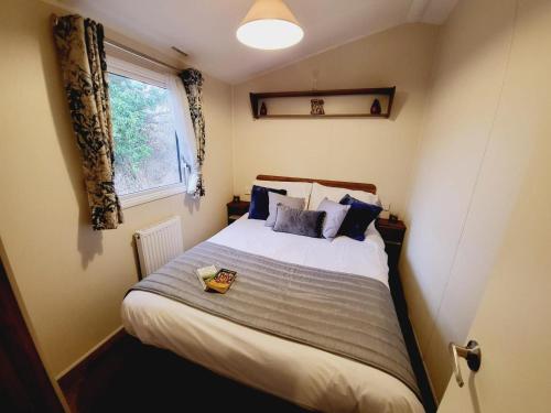 uma cama num pequeno quarto com uma janela em Beautiful 8 Berth Caravan At Valley Farm Holiday Park, Essex Ref 46362v em Great Clacton