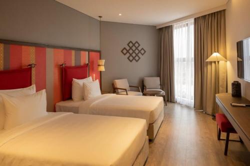 a hotel room with two beds and a television at M Continental by Mandala Mui Ne in Phan Thiet