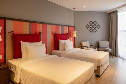 a hotel room with two beds with red accents at M Continental by Mandala Mui Ne in Phan Thiet