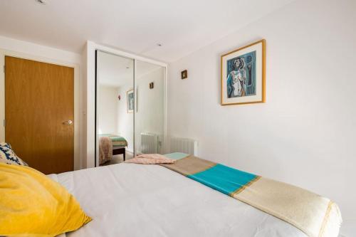 a bedroom with a bed with a yellow and blue blanket on it at Wild Roses Serviced Apartments - City Airport in North Woolwich