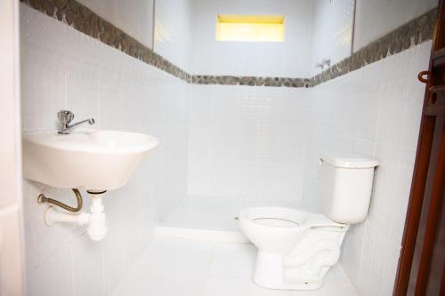 Baño blanco con lavabo y aseo en Quinuawasi House, en Ocosuyo