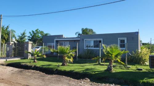 a house with palm trees in front of it at Complejo de casas en Pueblo Centenario in Santa Isabel