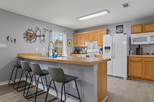 a kitchen with a white refrigerator and bar with stools at Waterfront Home with Pool, Hot Tub and Game Area in Shoreline Park
