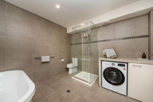 uma casa de banho com uma máquina de lavar roupa e um chuveiro em Esplanade Escape to the Brighton Beach Boxes em Melbourne