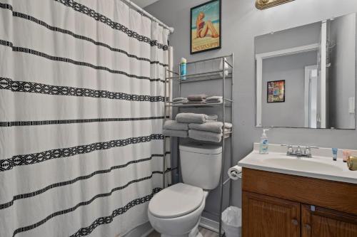 a bathroom with a toilet and a sink with a shower curtain at Waterfront Home with Pool, Hot Tub and Game Area in Shoreline Park