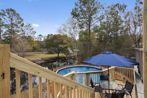 a deck with an umbrella next to a swimming pool at Waterfront Home with Pool, Hot Tub and Game Area in Shoreline Park