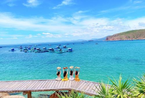 Hòa Lợi Hotel في كوي نون: مجموعة من الأحذية يجلسون على الرصيف مع المحيط