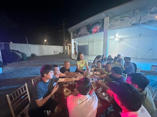 a group of people sitting around a table at night at Ngọc Dung Mall Homestay in Tân Phú