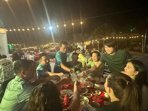 un grupo de personas sentadas alrededor de una mesa comiendo en Ngọc Dung Mall Homestay, en Tân Phú