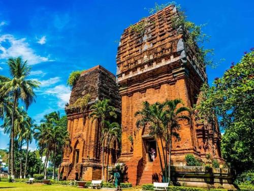 wysoki budynek z palmami przed nim w obiekcie Hòa Lợi Hotel w mieście Quy Nhơn