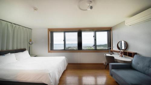a bedroom with a bed and a couch and windows at 丘の上の隠れ家邸宅 Villa VIEW in Nanjo