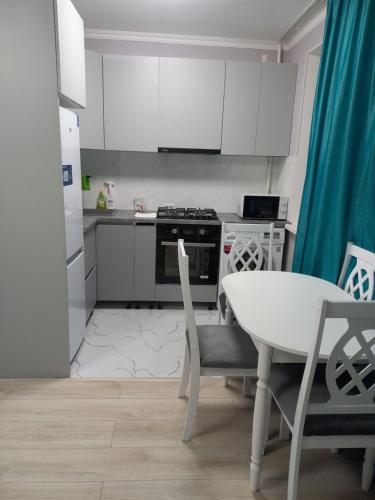 una cucina con mobili bianchi, tavolo e sedie di Apartments a Astana