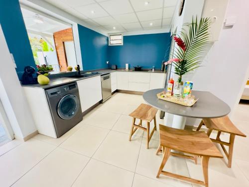 a kitchen with a washing machine and a table at Maison T3 Nid Bleu - Piscine Privée in Le Marin