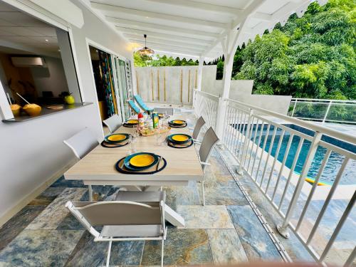 a table on the balcony of a house at Maison T3 Nid Bleu - Piscine Privée in Le Marin