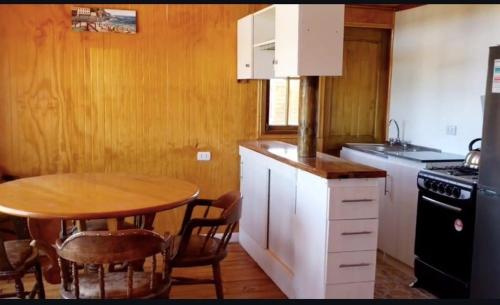 eine Küche mit einem Holztisch sowie einem Tisch und Stühlen in der Unterkunft Cabañas Laguna Seca 