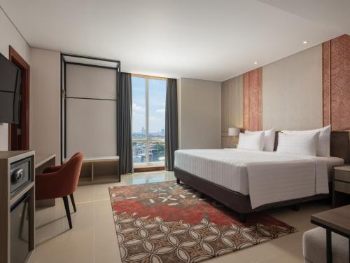 スラバヤにあるホテル サンティカ プレミア グベン スラバヤのベッドとテレビが備わるホテルルームです。