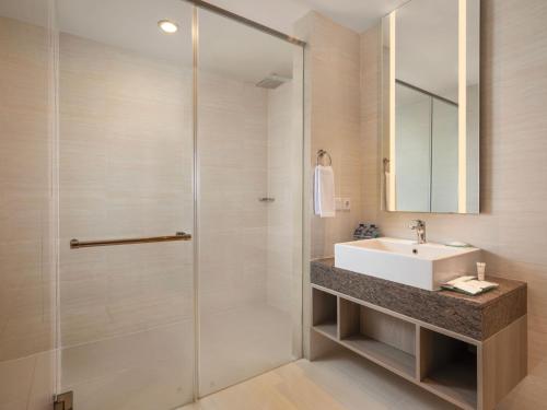 a bathroom with a sink and a shower at Hotel Santika Premiere Gubeng Surabaya in Surabaya