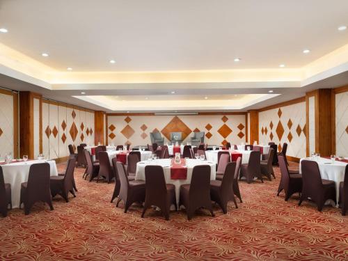 a banquet hall with white tables and chairs at Hotel Santika Premiere Gubeng Surabaya in Surabaya