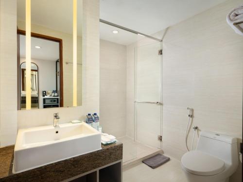 a bathroom with a sink and a shower and a toilet at Hotel Santika Premiere Gubeng Surabaya in Surabaya