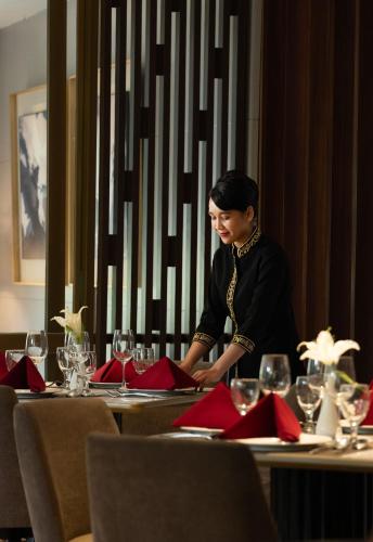 a woman sitting at a table with red napkins at Hotel Santika Premiere Gubeng Surabaya in Surabaya