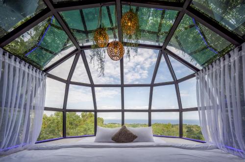 a bed in a room with a large window at Airship Bali by Alex Villas in Kuta