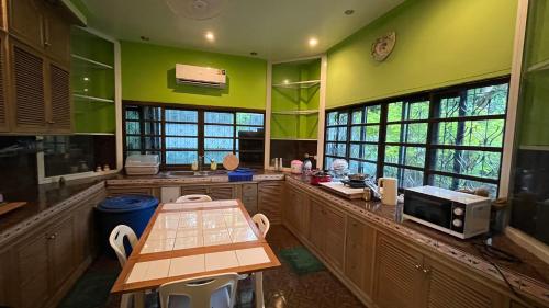 cocina con paredes verdes, mesa y microondas en Pattaya Golden view pool villa, en Ban Nong Srah