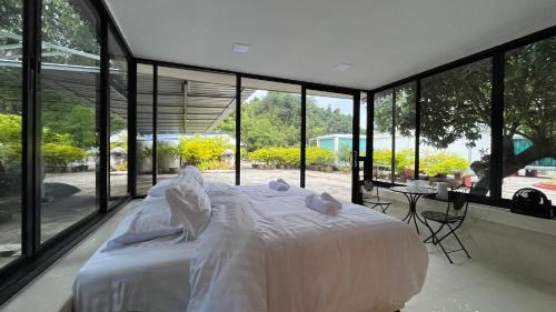 1 dormitorio con 1 cama blanca grande y ventanas grandes en Pattaya Golden view pool villa, en Ban Nong Srah