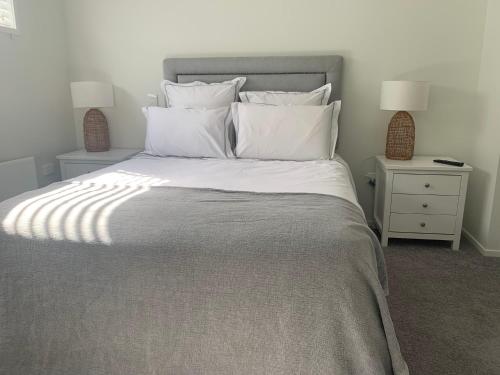 um quarto com uma cama grande e almofadas brancas em The Gate House em Tauranga