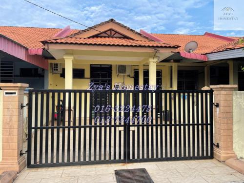 een huis met een zwarte poort ervoor bij Zya'S Homestay Gong Badak in Kampong Bukit Berangan
