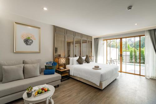 - une chambre avec un lit et un canapé dans l'établissement Bella Nara Phuket Naiyang Beach, à Nai Yang Beach